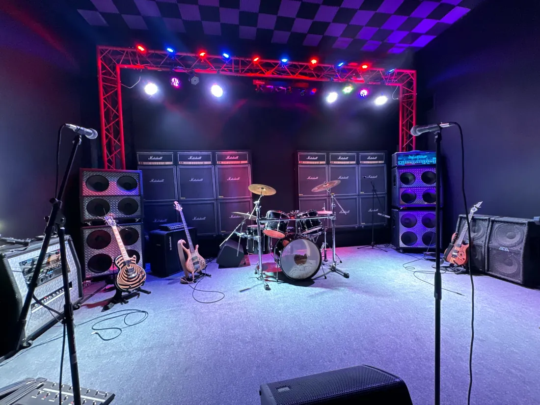 The VIP Studios stage with truss lighting, Marshall stacks, drum kit and guitars